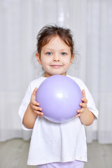 Young girl smiling, looking at the camera, and holding a lavender ball