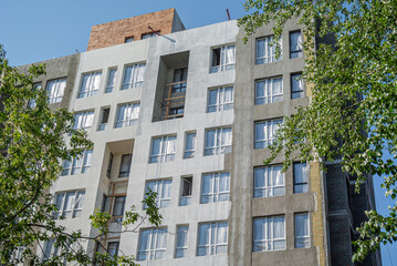 Construction work on the exterior cladding. Laying of thermal insulation material on the walls. Home insulation. Plastering the walls. Windows of a multi-storey house under construction.