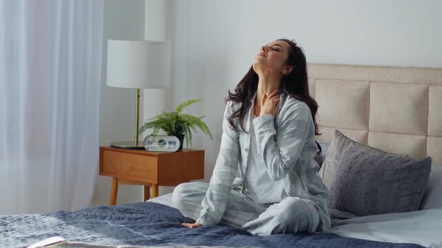 Caucasian woman in morning in bed feeling neck pain back ache discomfort uncomfortable mattress orthopedic health problem female girl waking up moving head circle yoga in bedroom lady awaking happy