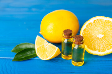 Lemon essential oil in a bottle with sliced ​​lemon and leaves on a wooden background. Lemon oil. Perfume bottle with aromatic essential oil. Serum, lemon extract. Vitamin C. Natural cosmetics. 