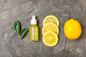 Lemon essential oil in a bottle with sliced ​​lemon and leaves on a wooden background. Lemon...
