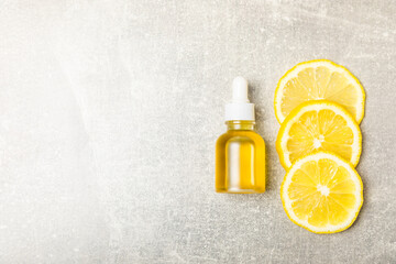 Lemon essential oil in a bottle with sliced ​​lemon and leaves on a wooden background. Lemon oil. Perfume bottle with aromatic essential oil. Serum, lemon extract. Vitamin C. Natural cosmetics. 