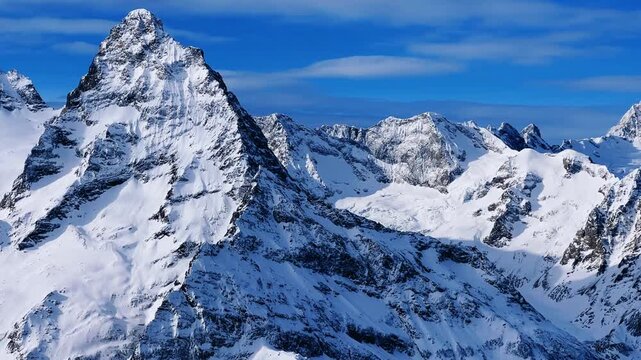 View of Dombay glaciers and mountain peaks in the winter sun. Panorama of the snow-capped Caucasus Mountains in sunny weather. Dombay-Ulgen and Moussa-Achitara mountains. Ski resort in Russia.