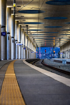 Empty modern train station with two tracks in a gentle curve at blue hour. View from the ground, with a yellow safety lane line.