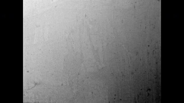Old film, serious looking thug walking down village street. Aged, grainy transitions create vintage, dramatic atmosphere. Tension, danger, criminal persona. Old film. Archival retro. Vintage archive