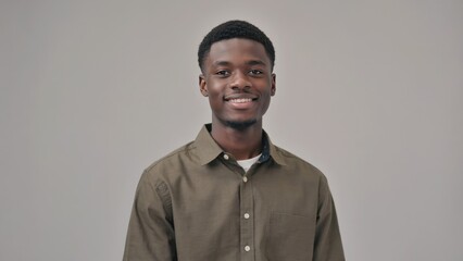 Obraz premium Young man smiling in olive shirt against gray background