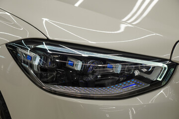 Close up detail of the BI-LED headlights modern white car. Exterior closeup detail. Front headlights of car. BI-LED headlights of a modern and expensive white car. Front BI-LED headlight on sport car.