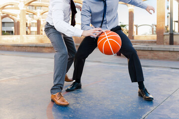Naklejka premium Close -up of two unrecognizable businessmen dribbling a basketball in formal clothing
