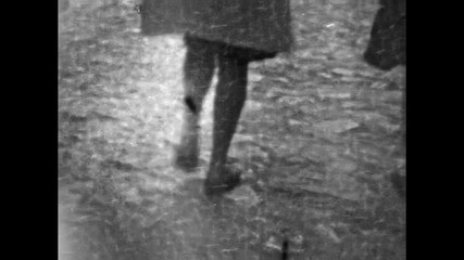 Close up, female legs walking on wet city street after rain. Urban commute, anonymous pedestrian movement, daily routine in autumn. Colleagues move to work. Archival old film. Vintage archive 