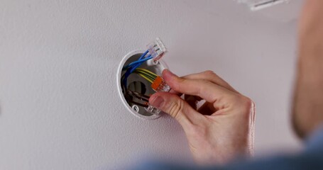 Electrician connects wires with splicing connectors in drywall junction box. electrical services