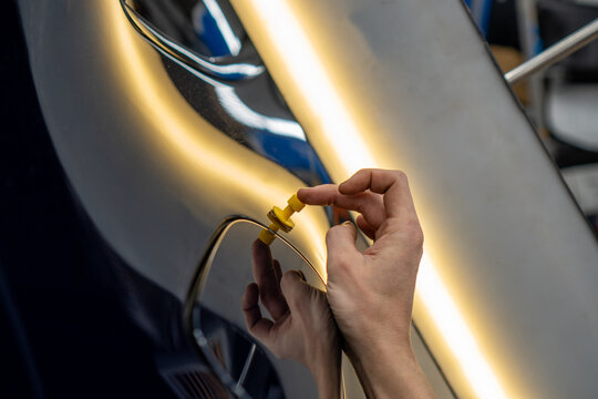 Process of paintless dent repair on car body. The mechanic at the auto shop with tools to repair dents in car body. Body repair. A specialist repairs a dent on the car body without painting. PDR. 