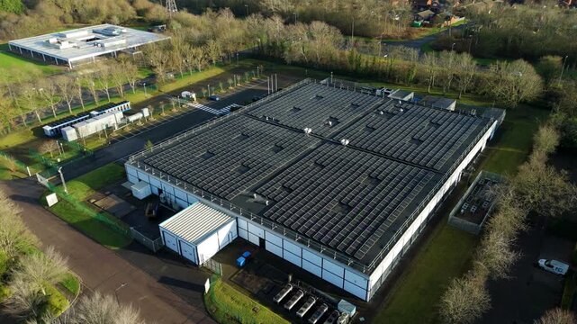 Aerial view of data center buildings with solar panels, surrounded by trees and roads, showcasing the energy infrastructure, Milton Keynes, England, United Kingdom.