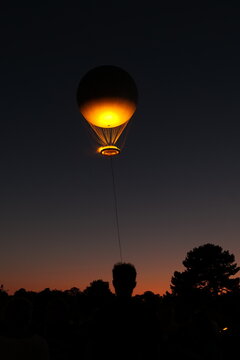 Une silhouette d'une personne avec un t&eacute;l&eacute;phone portable devant le ballon de la flamme olympique au dessus du ciel de nuit de Paris