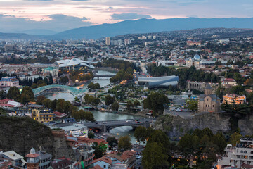 Tbilisi Cityscape Panorama With Peace Bridge And Metekhi Church At Twilight