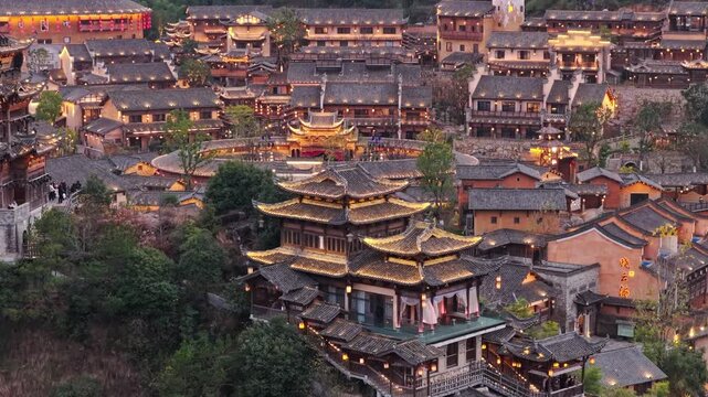 Aerial view of the Wangxian Valley's traditional buildings, with warm lights contrasting against the dark roofs, Wangxian Valley, China.