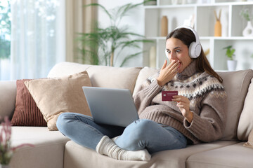Amazed woman in winter paying media online at home