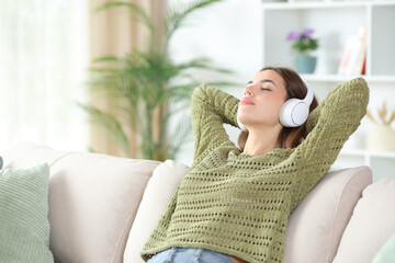 Woman in green relaxing on a couch listening audio on headphone