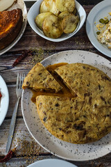 Slicing spanish tortilla de patatas with tapas and fried potatoes
