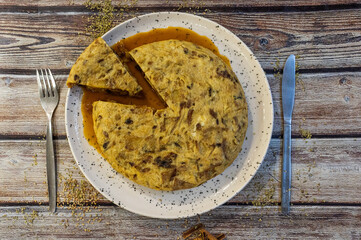Spanish omelet with sauce on rustic wooden table