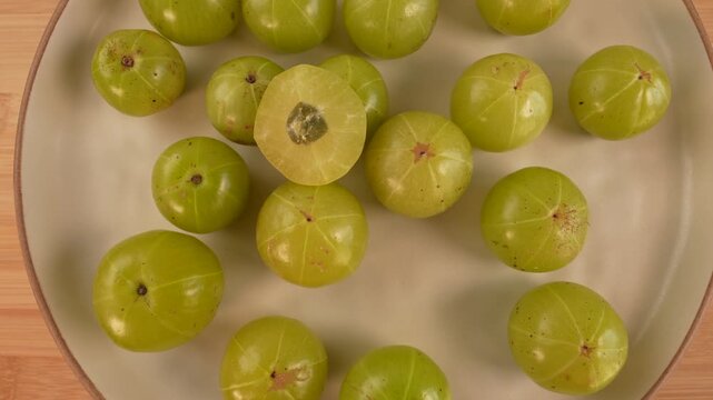 Indian gooseberry fruits on plate rotation top view. Selective focus. Amla. Phyllanthus emblica.