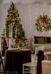 A bright room with a window and a decorated Christmas tree in the corner