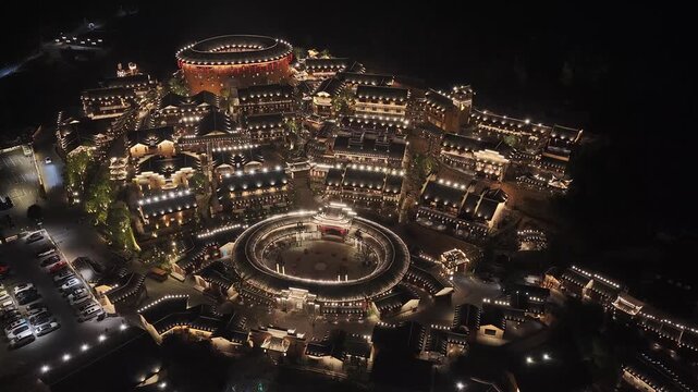Aerial view of the Wangxian Valley at night, lit by twinkling lights, creating a warm glow amidst the dark surroundings, Wangxian, China.