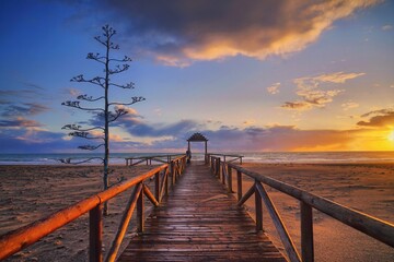 Obraz premium Stunning sunset over Cadiz beach, with golden hues reflecting on the Atlantic, framed by serene sands and historic skyline.