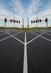 Fototapeta premium A complex view of converging asphalt surfaces forming a major roadside intersection. Traffic control infrastructure stands ready against the sky ,construction ,pole ,access