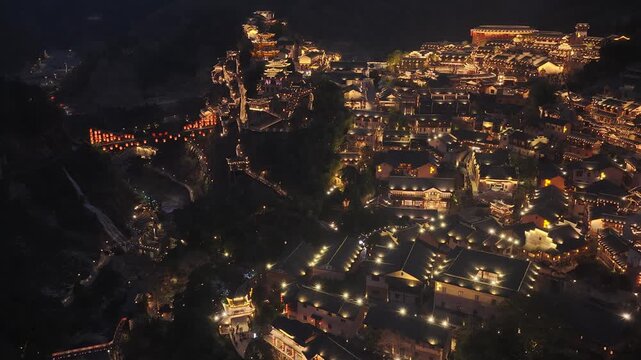 Aerial view of Wangxian Valley illuminated with a warm glow, nestled between dark hillsides, creating a striking contrast, Wangxian, China.