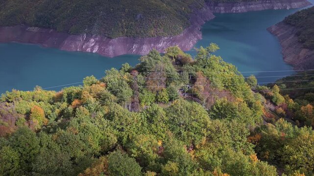 Aerial video of Fierza Lake with turquoise waters and autumn forests along the steep mountain slopes.