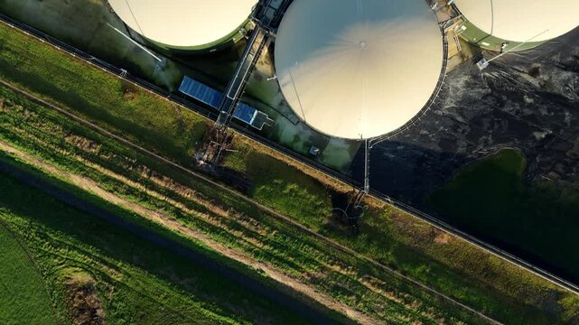 Aerial view of biogas plant domes contrasting with the vivid green fields and dark sludge ponds, Wisbech, England, United Kingdom.