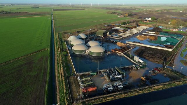 Aerial view of a biogas plant with dome-shaped structures amidst lush green fields, creating a stark contrast, Wisbech, England, United Kingdom.