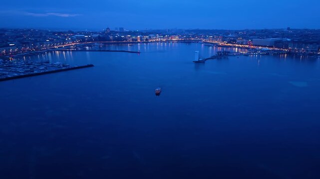 Aerial view of boat sailing on the serene Lake Geneva at twilight, with the city lights twinkling along the shore, Geneva, Geneva, Switzerland.