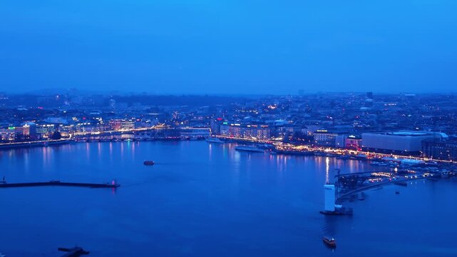 Aerial view of Geneva's illuminated cityscape reflecting on Lake Geneva's dark waters, a stunning contrast of light and shadow, Geneva, Geneva, Switzerland.