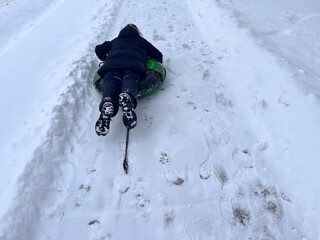 Winter. Winter fun. A teenage boy is trying to ride a tube on a snowy road.