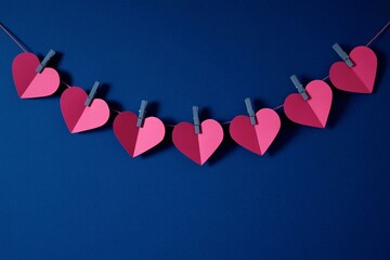 Minimal festive decoration with pink heart garland on blue background