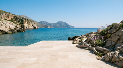 a serene coastal scene with clear blue water, rugged cliffs, and distant mountains under a bright blue sky