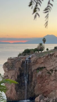 Small waterfall in Falez Park, Muratpasa, Antalya. Sunset light behind distant mountains, Mediterranean Sea in the background, urban nature, and coastal landscape