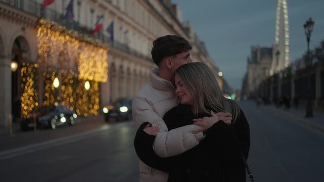 A romantic couple is seen hugging on a street in Paris France at dusk The Eiffel Tower is visible in the background and the scene is lit with soft warm lighting The clip captures a moment of love and 