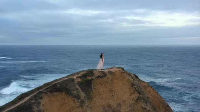 Bride on cliffside journey: capturing serenity and nature's majesty