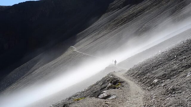 Hikers on a misty mountain trail navigating steep rocky path
