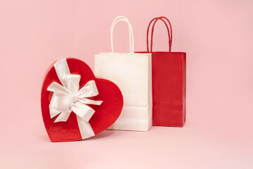 A holiday backdrop with a heart-shaped cardboard box with a bow, a gift bag on a pink background. Great for holidays, Mother's Day, weddings, or Valentine's Day.