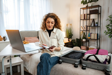 Young woman packing suitcase for travel planning vacation