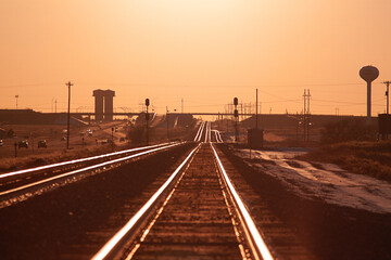 Railroad tracks stretch toward the horizon at sunset near Amarillo, Texas. Warm light reflects off the steel rails, creating strong leading lines and a sense of distance. 