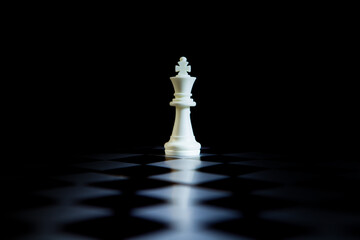 Chess king on the chessboard, black background, business concept