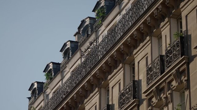 A panning shot showcases the classic Parisian architecture highlighting a building with ornate balconies dormer windows and intricate ironwork The scene captures the essence of Paris France a popular 