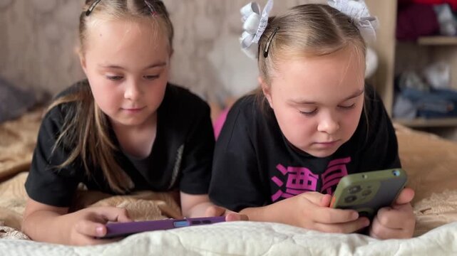 Two European twin girls playing video games on phone close-up