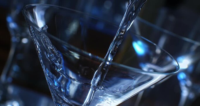 Slow motion 1000 fps of clear vodka being poured into a martini glass. Blurred elegant bar background, soft intimate lighting, luxury nightlife, mixology and premium drink concept.