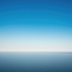 Fototapeta premium A dramatic empty blue sky fading into a misty pale horizon line over a vast, featureless expanse of water below ,quiet ,tranquil ,simple