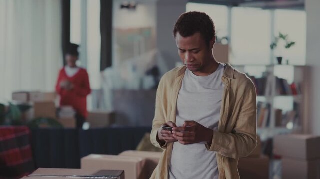 Man checks phone, Man reviews order details attentively, Individual examining phone in workspace environment